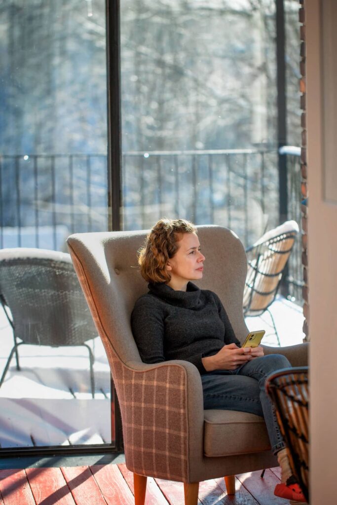 gościni odpoczywająca w fotelu w Rajskich Jabłkach - dom gościnny tylko dla dorosłych Pogórze Izerskie, zimowe światło w Pławnej Górnej na Dolnym Śląsku.