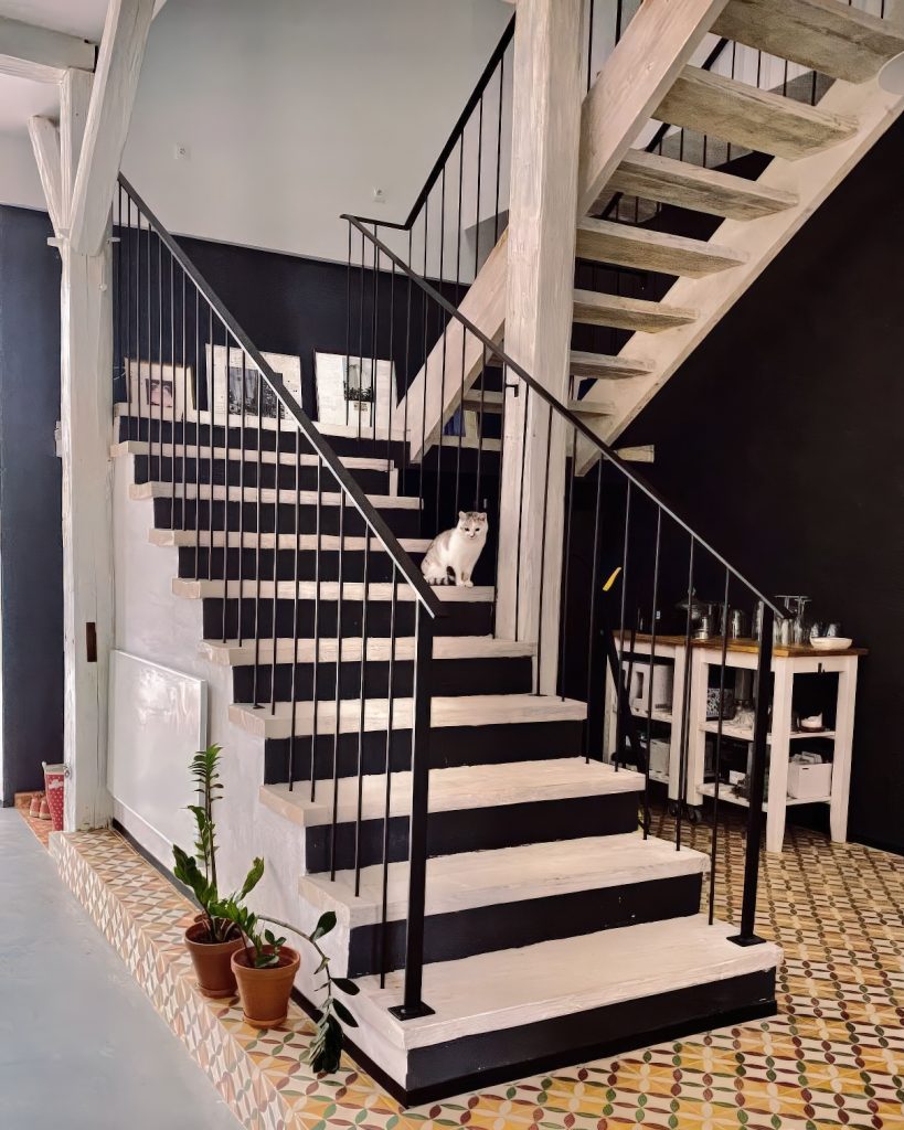 Drewniane schody w domu gościnnym dla dorosłych Rajskie Jabłka w Pławnej Górnej na Dolnym Śląsku, na stopniu siedzi kotka Lilu.